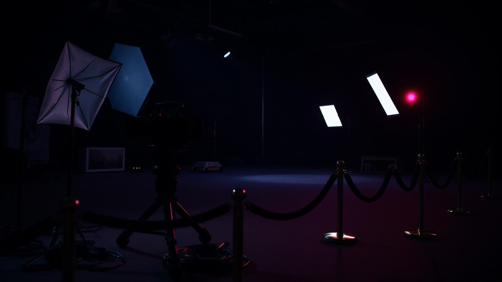 Empty professional film set at night with cinema camera, lighting rigs and cordon rope